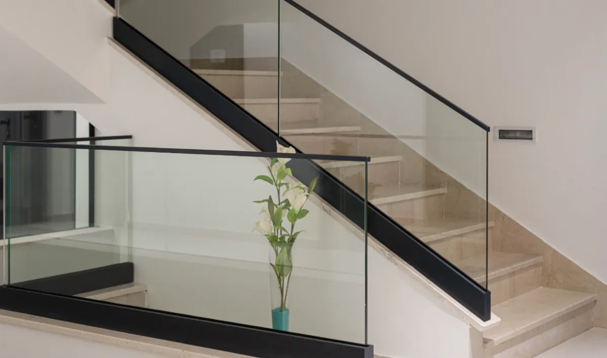 Glass stair railing with aluminium profile and base rail, showing mechanical nut-bolt assembly system for staircase applications